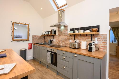 a kitchen with gray cabinets and a brick wall at Old Town Loft in Cupar