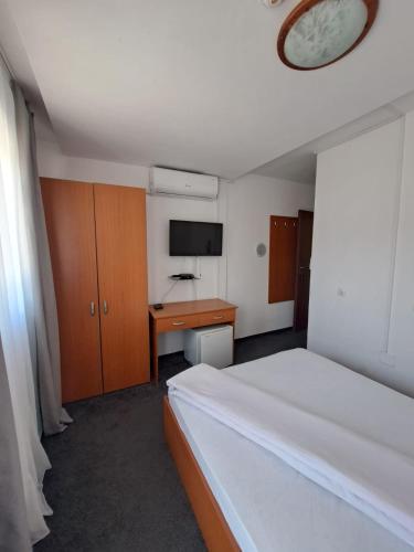 a bedroom with a bed and a desk and a clock at Hotel Pescarus Port Bicaz in Bicaz