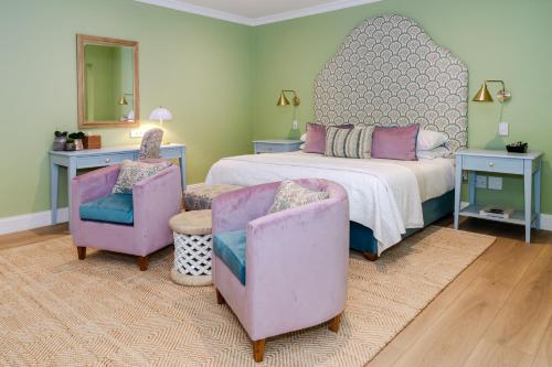 a bedroom with a bed and two chairs and a mirror at Last Word Franschhoek in Franschhoek