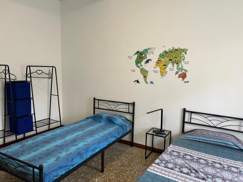 Cette chambre comprend 2 lits et une carte du monde sur le mur. dans l'établissement Tra mare e arte, à Lido di Ostia