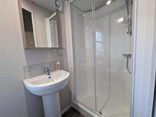 een witte badkamer met een wastafel en een douche bij The Manor in Dunoon