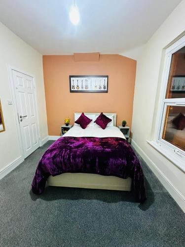 a bedroom with a bed with a purple blanket at Elm Vale Lodge in Liverpool