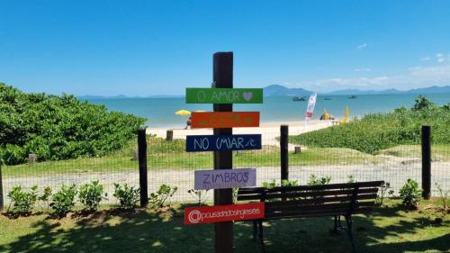 a pole with street signs on it next to a bench at Pousada dos Ingleses in Bombinhas