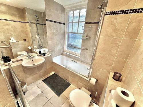 a bathroom with a toilet and a sink and a shower at Alluring 2-Bed, 2-Bath Flat on High Street Kensington, Near Kensington Palace in London