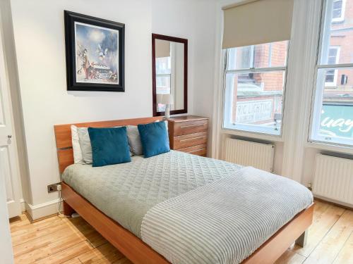a bedroom with a bed with blue pillows at Alluring 2-Bed, 2-Bath Flat on High Street Kensington, Near Kensington Palace in London