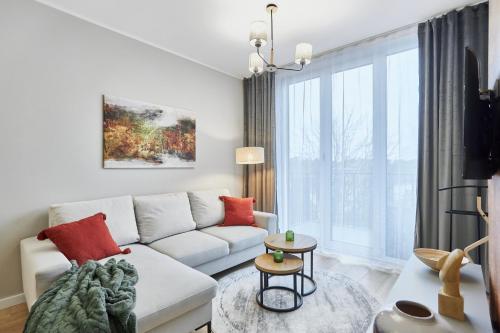 a living room with a white couch and a large window at Apartamenty Świnoujście - Seaside Garden 59 in Świnoujście