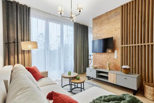 a living room with a white couch and a tv at Apartamenty Świnoujście - Seaside Garden 59 in Świnoujście