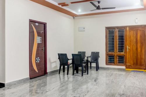 a dining room with black chairs and a wooden door at OYO Akshaya Kanuru in Gunadala
