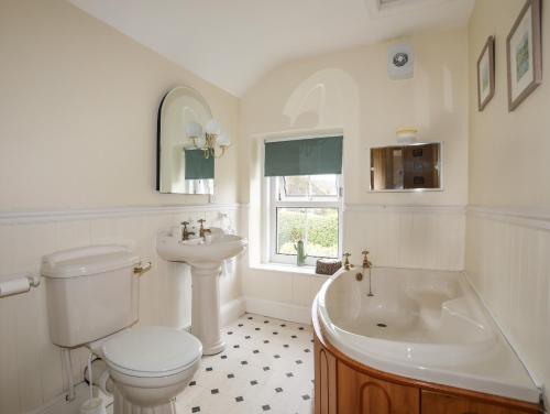 La salle de bains est pourvue de toilettes, d'un lavabo et d'une baignoire. dans l'établissement Amelie Cottage, à Beaumaris