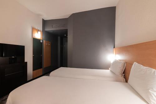 a hotel room with two beds and a television at Ibis Astana in Astana