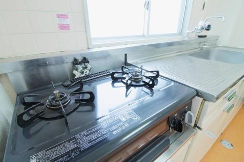 - une cuisine équipée de plaques de cuisson et d'un évier dans l'établissement Ishiki - Best location 2 min HiroshimJR station, Up to 10 ppl, à Hiroshima