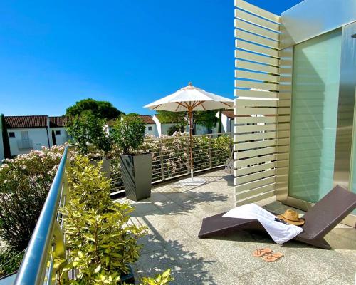einen Balkon mit einem Stuhl und einem Sonnenschirm in der Unterkunft Art&Park Hotel Union Lido in Cavallino-Treporti
