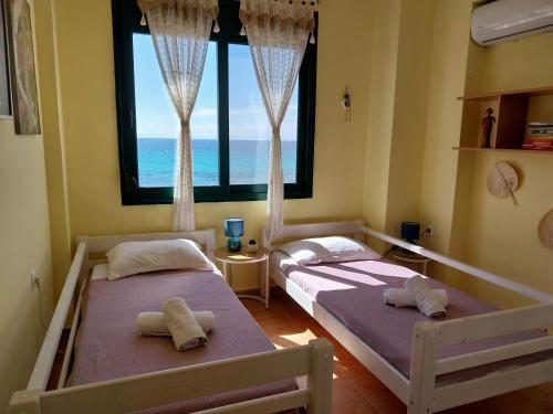 two beds in a room with a view of the ocean at Villa 3Ω in Nea Skioni