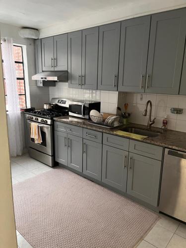 a kitchen with gray cabinets and a sink at Stay Rego Park in Rego Park