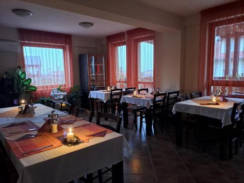 a dining room with tables and chairs and windows at Pension Panorama in Odorheiu Secuiesc