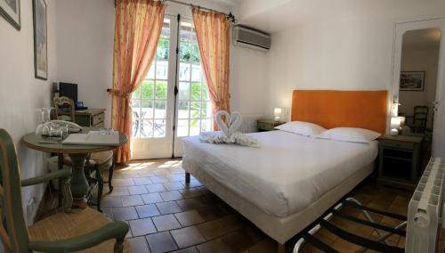 a bedroom with a bed and a table and a window at Hôtel Jas Neuf in Sainte-Maxime