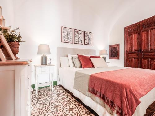 um quarto branco com uma cama e um cobertor vermelho em Descanso y paz en la Juderia de Carmona em Carmona
