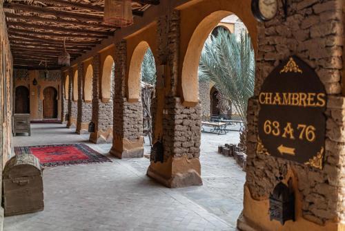 a building with a sign in the middle of a courtyard at Kasbah Hotel Xaluca Arfoud in Erfoud