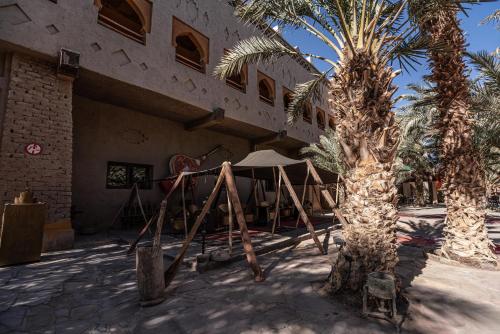 a building with a palm tree in front of it at Kasbah Hotel Xaluca Arfoud in Erfoud