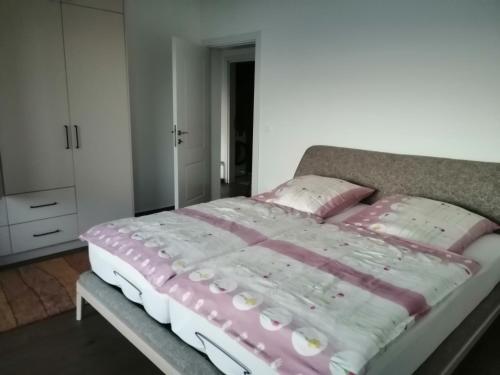 a bed with pink and white sheets and pillows at Apartmani Seaside in Dobra Voda