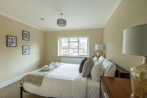 een slaapkamer met een wit bed en een raam bij Lovely 2BR in peaceful Hampstead, NW London in Londen