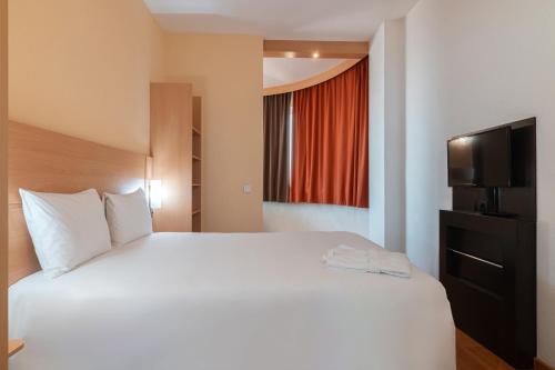 a bedroom with a large white bed and a window at Ibis Astana in Astana