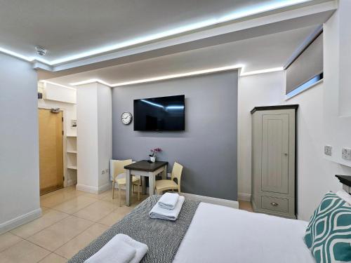 a bedroom with a bed and a table with a tv on the wall at London Stay Apartments in London