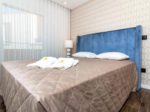 a large bed with a blue headboard and white pillows at Sea la Vie House by Stay ici in Albufeira