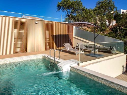 a swimming pool with chairs and a house at Sea la Vie House by Stay ici in Albufeira