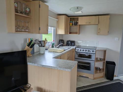 a kitchen with wooden cabinets and a stove top oven at The Hidden Gem in Galloway Forrest in Balminnoch