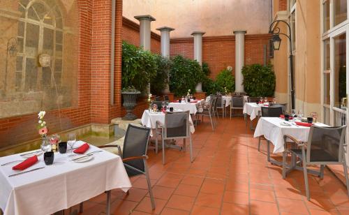 a restaurant with tables and chairs with white table cloth at Plaza Hotel Capitole Toulouse in Toulouse