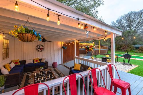 a patio with red chairs and a couch on a porch at Pool, Gameroom & Minigolf Enchanting Texas Home in San Antonio