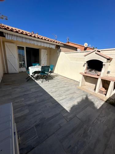 een patio met een tafel en stoelen op een huis bij La Discrète toute équipée avec piscine in Gruissan