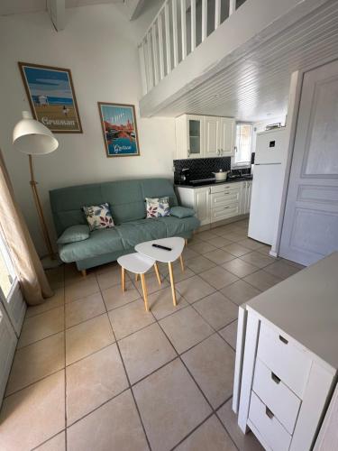 een woonkamer met een groene bank en een tafel bij La Discrète toute équipée avec piscine in Gruissan