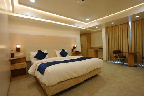 a hotel room with a large bed with blue pillows at Hotel 6 Seasons, Koregoan Park, Pune in Pune