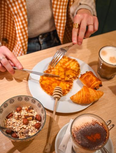 a person eating food on a table with a plate of food at Hôtel Suzane in Angers