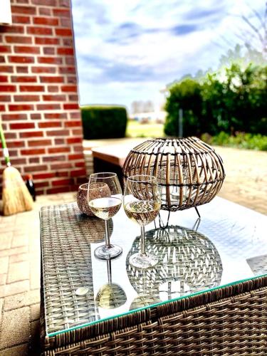 two glasses of white wine sitting on a table at Seeliebe, 300 Meter zum Wasser, mit Terrasse und Garten in Lembruch