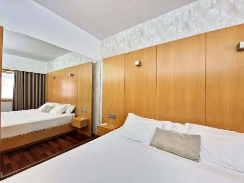 een slaapkamer met 2 bedden en houten kasten bij Hotel Dunas d'Ovar in Ovar