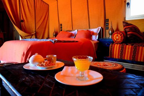 a bedroom with a bed and two plates of food on a table at Roses desert camp in Merzouga