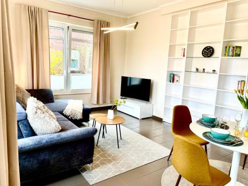 a living room with a blue couch and a tv at Seeliebe, 300 Meter zum Wasser, mit Terrasse und Garten in Lembruch