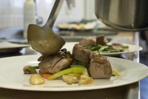 a spoon picking up food from a plate of food at Strandhotel Bos en Duin in Oostkapelle