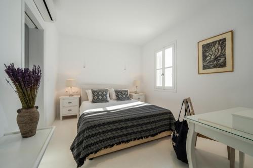 a white bedroom with a bed and a table at Astra House by Mykonos Mood in Mikonos