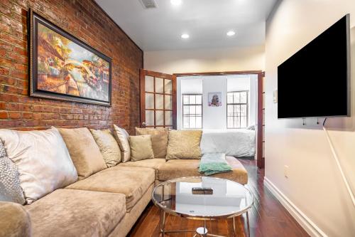 een woonkamer met een bank en een bakstenen muur bij The Nest- 1 bedroom 1 bath convenient and cozy apartment in Brooklyn