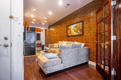 een woonkamer met een bank en een bakstenen muur bij The Nest- 1 bedroom 1 bath convenient and cozy apartment in Brooklyn