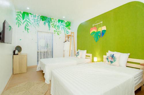 ハロンにあるNhà Mình Homestay Hạ Longの緑の壁のベッドルーム1室(ベッド2台付)