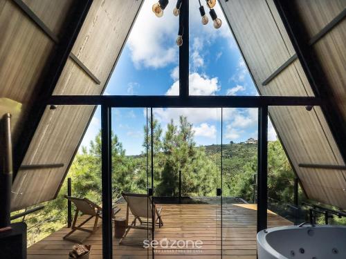 a bathroom with a large window and a tub at Chales Naturale - Campos do Jordão - CNA in Campos do Jordão