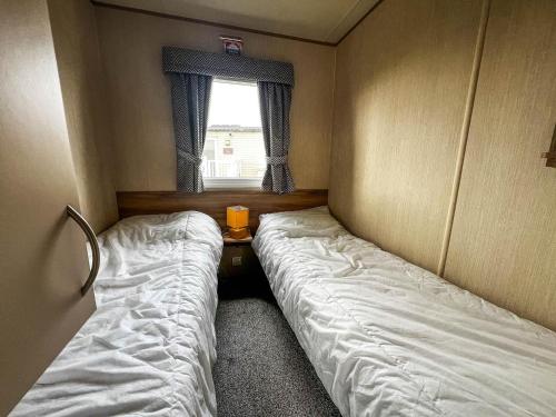 two beds in a small room with a window at Lovely 6 Berth Caravan With Wi-fi At Sand Le Mere In Yorkshire Ref 71091td in Tunstall