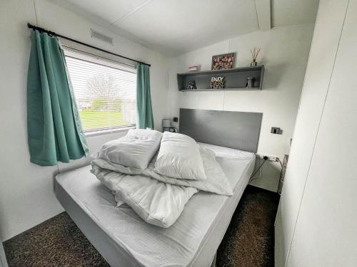 a bedroom with a bed with white sheets and a window at Homely Caravan At Sand Le Mere Holiday Park Ref 71018n in Tunstall