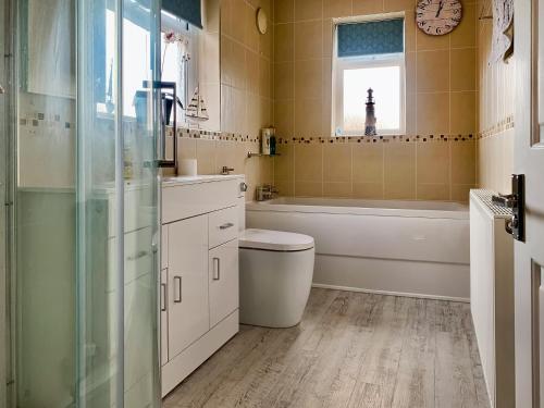 uma casa de banho com um WC, uma banheira e um relógio. em Joenina em Bridlington