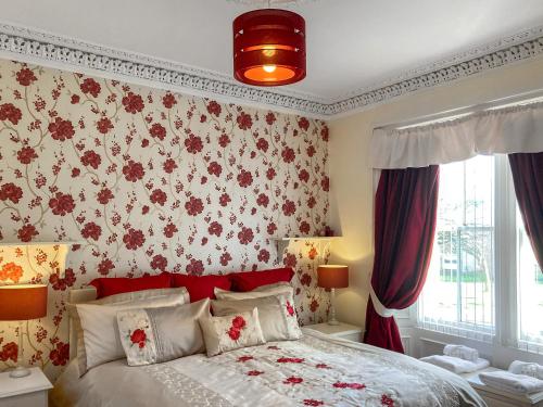 a bedroom with a bed with red floral wallpaper at Victorias Haven in Kirkcaldy